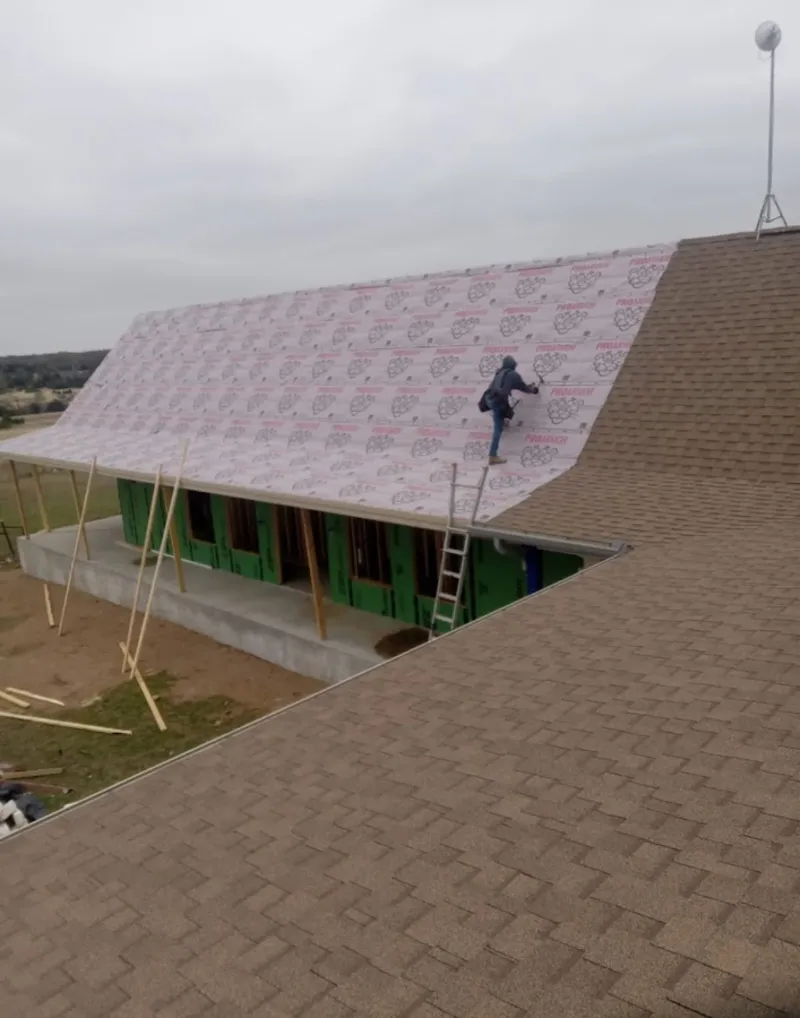 Worker preparing underlayment for a metal roof installation in Starkville